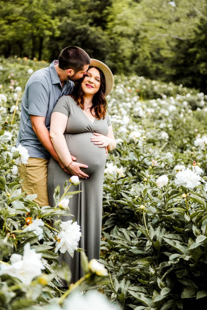 The Womb Room. A pregnant woman in a flower field with her husband