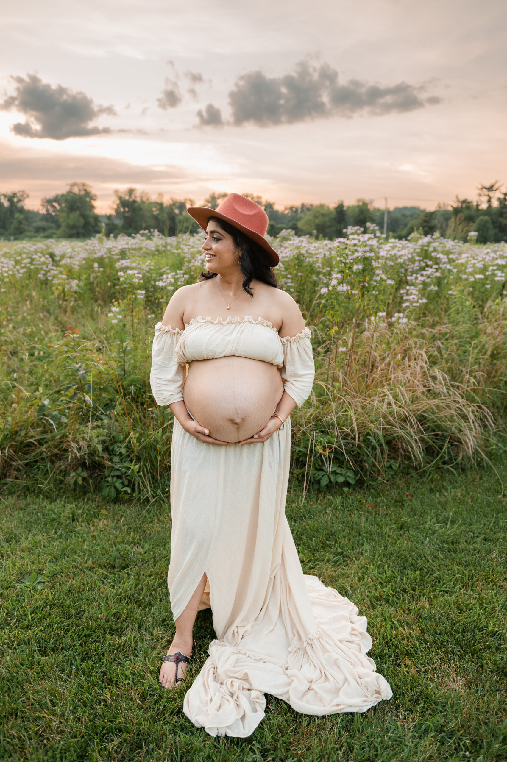 Pregnant woman wearing a soft neutral maternity dress during a peaceful outdoor photoshoot