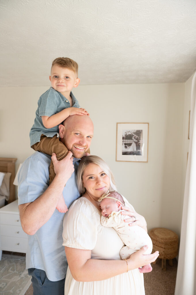“Parents holding their newborn during a family photo in the studio for families wanting help with gentle posing.”