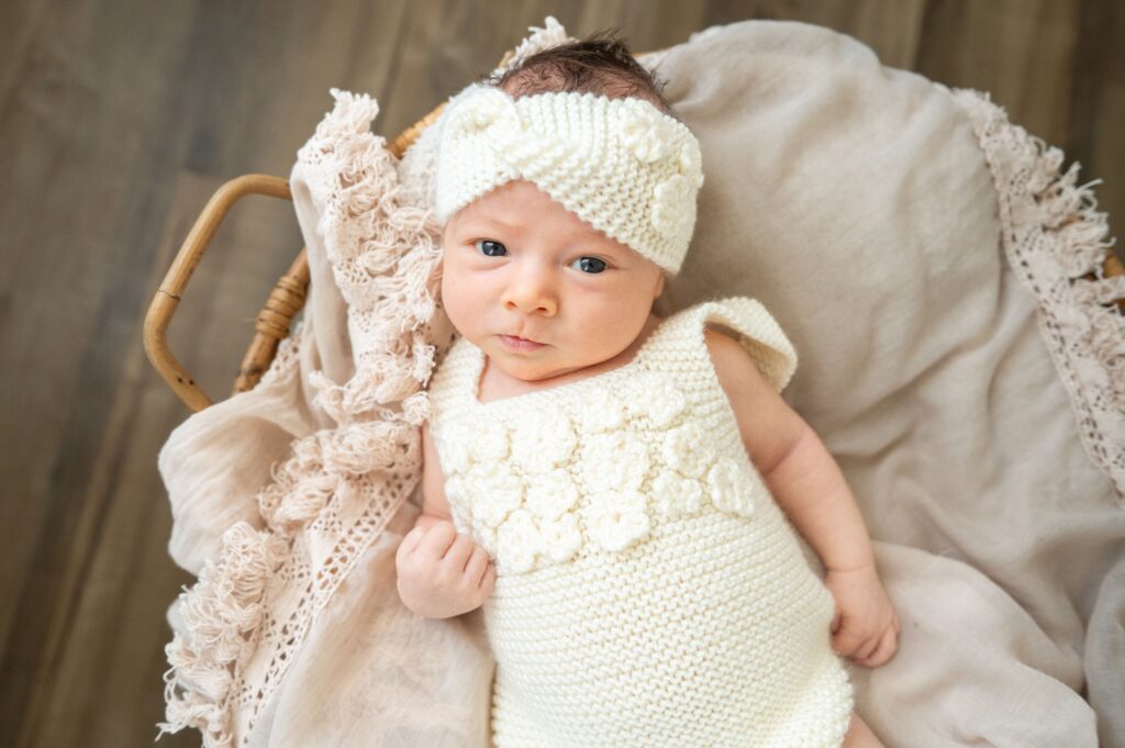 Newborn baby sleeping on a cream blanket during a lifestyle newborn photography session.