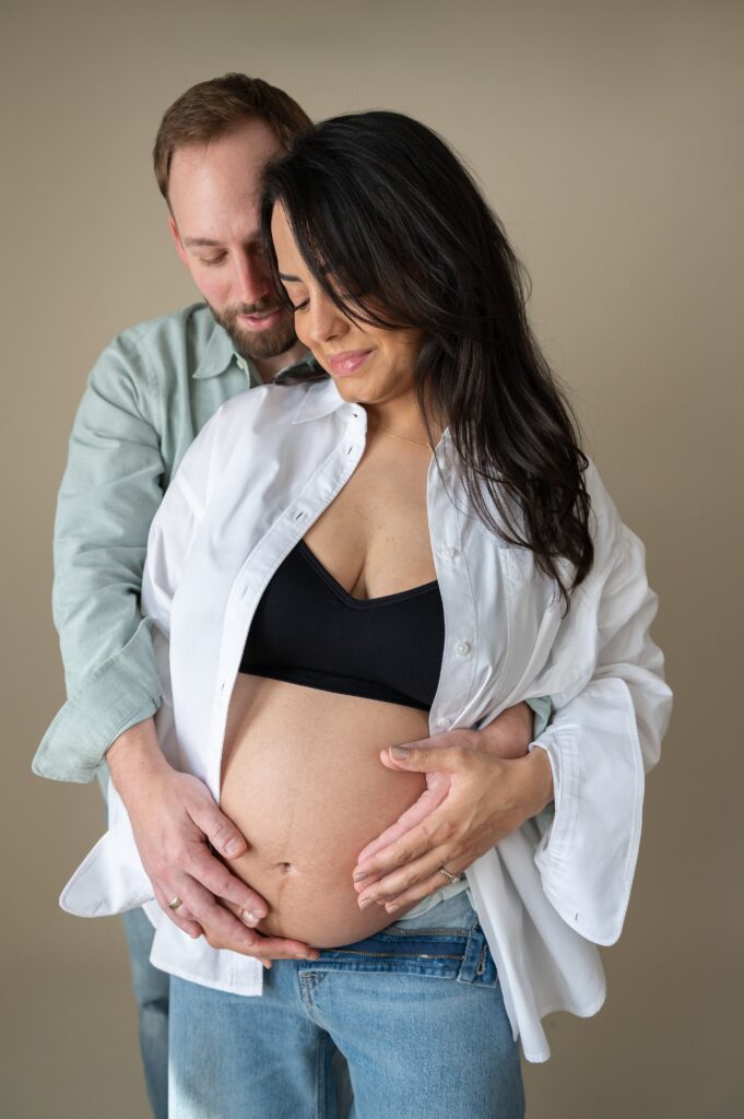 Pregnant mom and partner posing together during in studio maternity photos in Baltimore.
