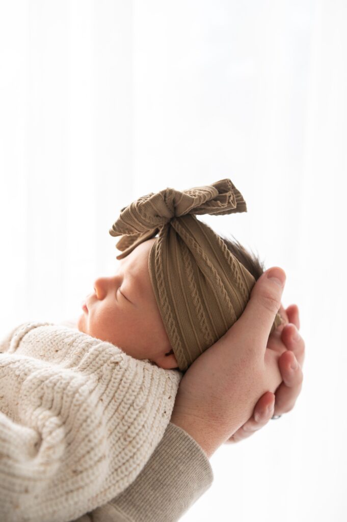Parents looking down at sleeping newborn in soft lifestyle newborn studio setup